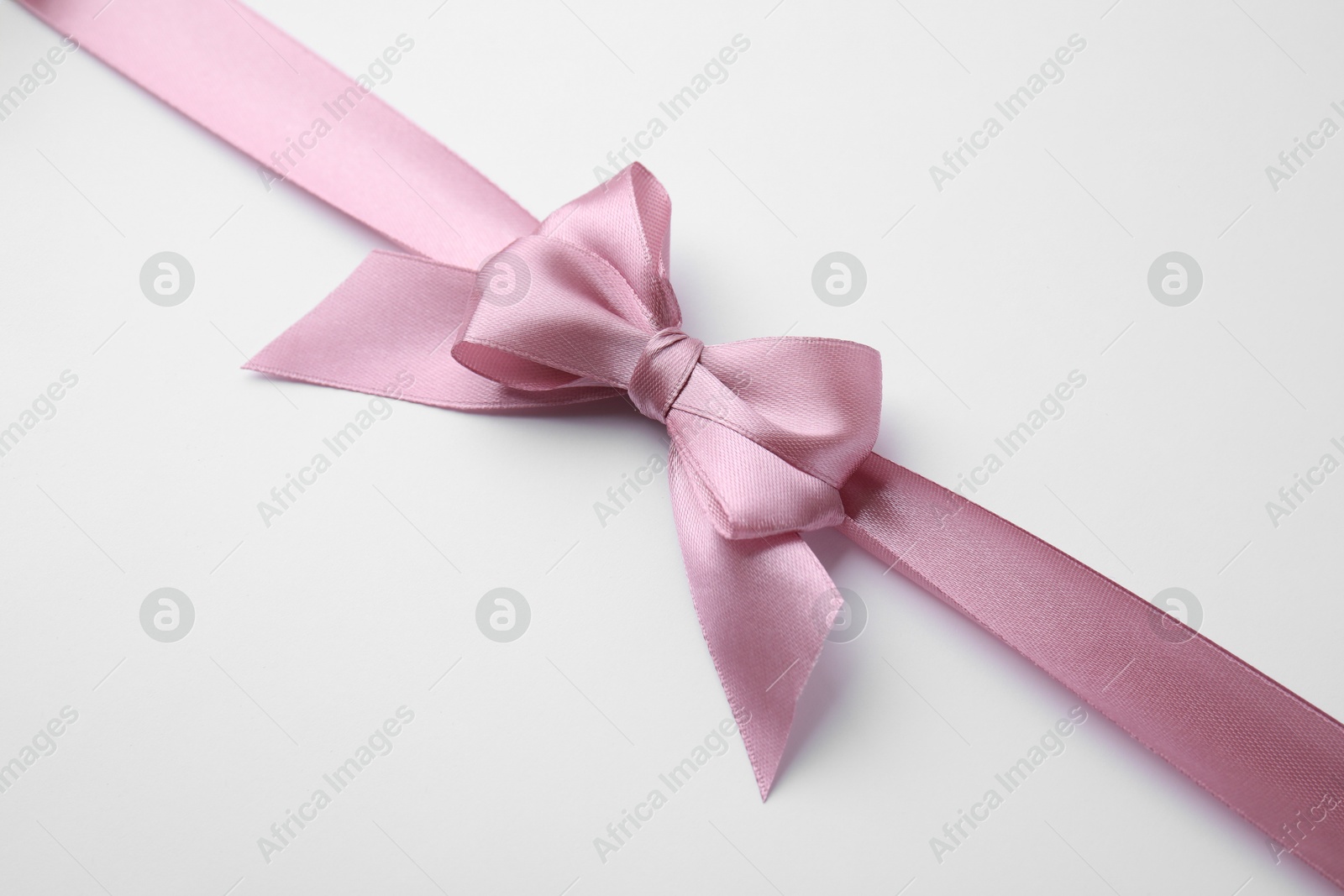 Photo of Pink satin ribbon with bow on white background