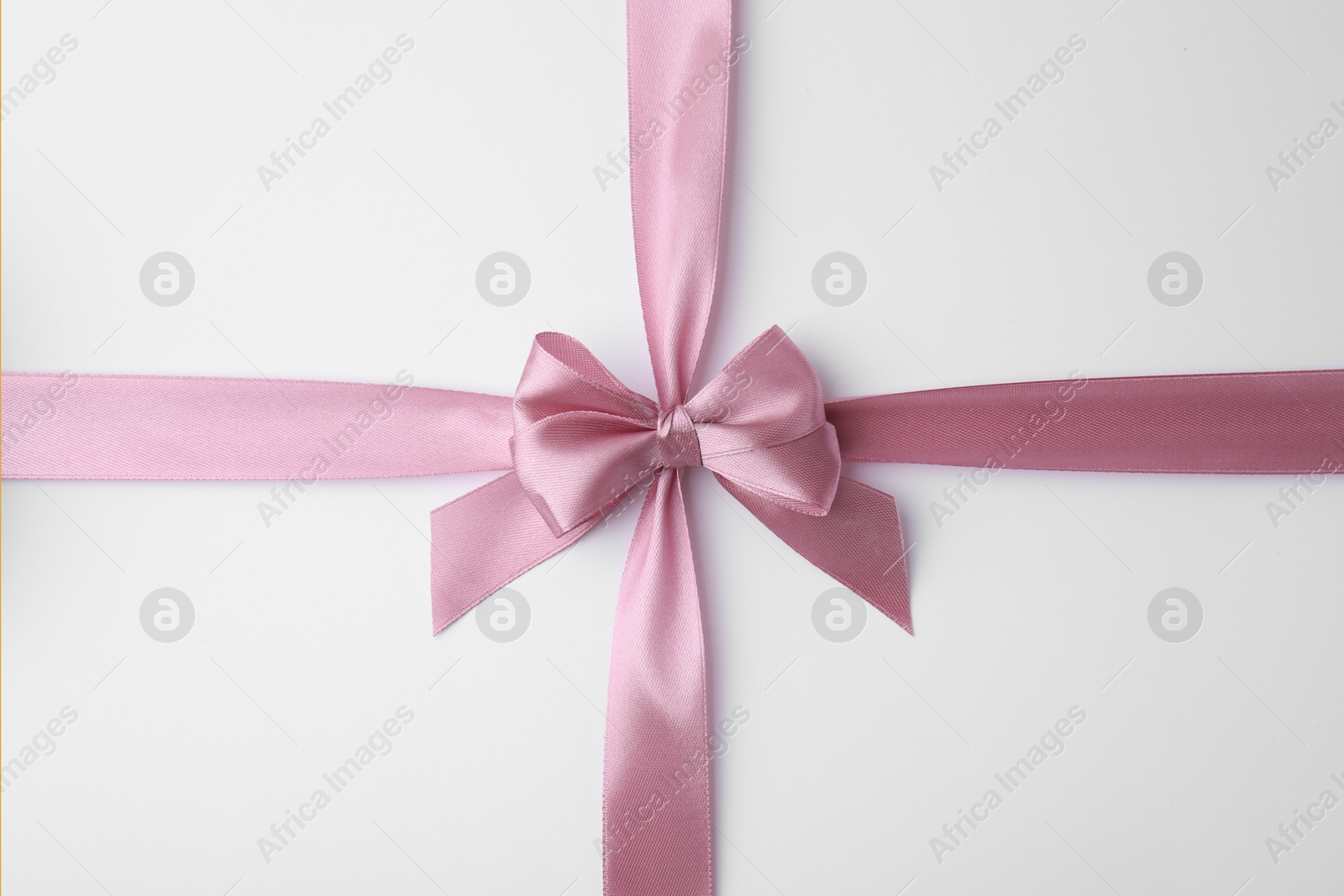 Photo of Pink satin ribbon with bow on white background, top view