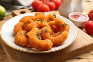 Tasty breaded fried shrimps served on wooden table, closeup