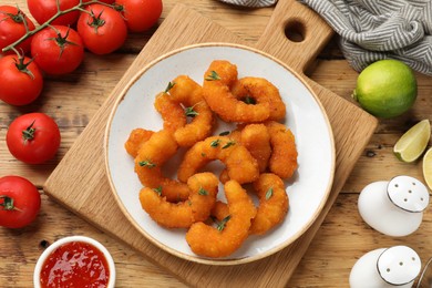 Photo of Tasty breaded fried shrimps served on wooden table, flat lay
