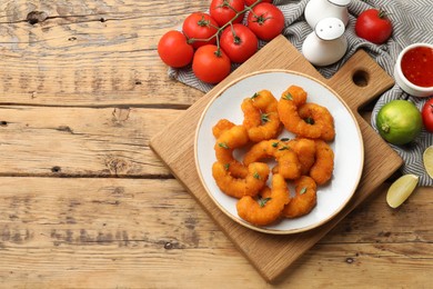 Photo of Tasty breaded fried shrimps served on wooden table, flat lay. Space for text