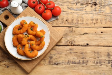 Photo of Tasty breaded fried shrimps served on wooden table, flat lay. Space for text