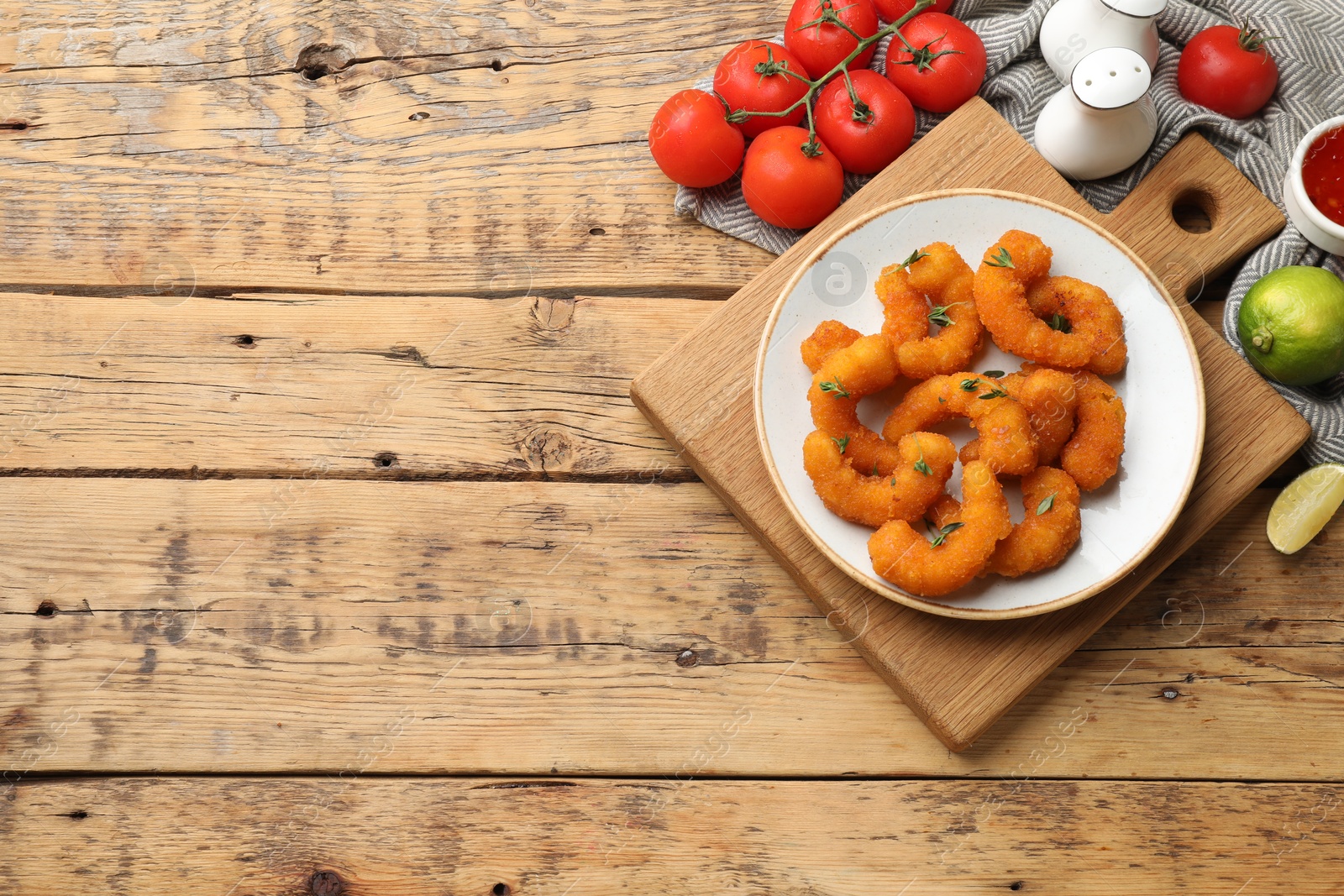 Photo of Tasty breaded fried shrimps served on wooden table, flat lay. Space for text