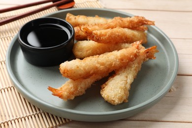 Tasty breaded fried shrimps served with sauce on light wooden table, closeup