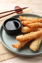 Photo of Tasty breaded fried shrimps served with sauce on light wooden table, closeup