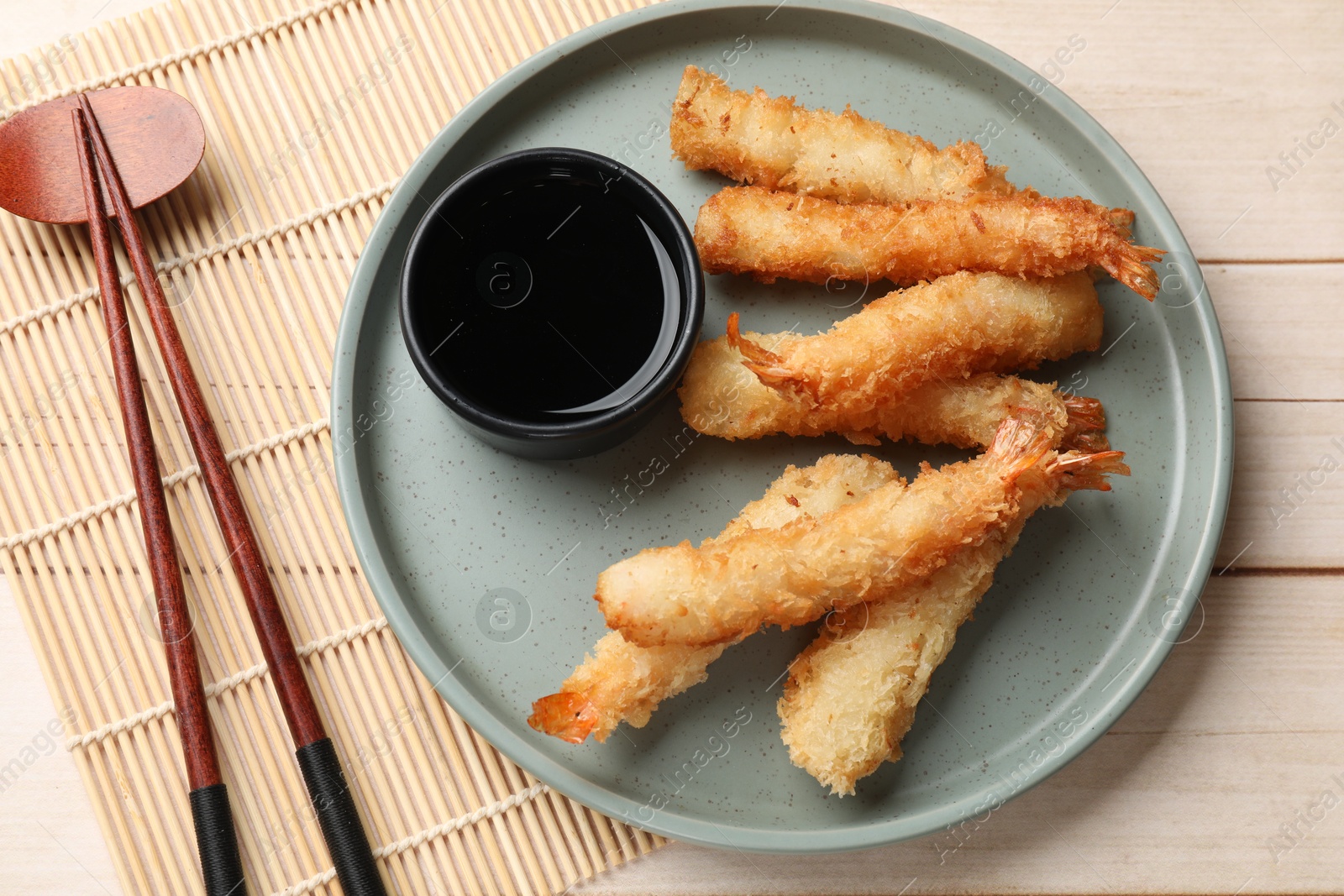 Photo of Tasty breaded fried shrimps served with sauce on light wooden table, top view