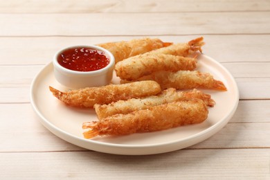 Tasty breaded fried shrimps served with sauce on light wooden table