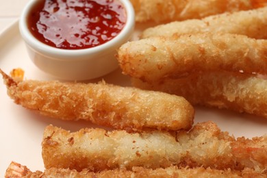 Tasty breaded fried shrimps served with sauce on plate, closeup