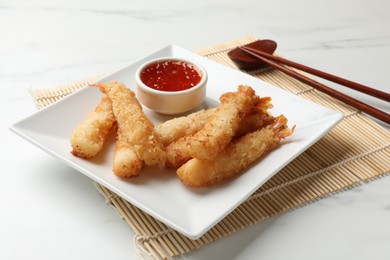 Tasty breaded fried shrimps served with sauce on white table