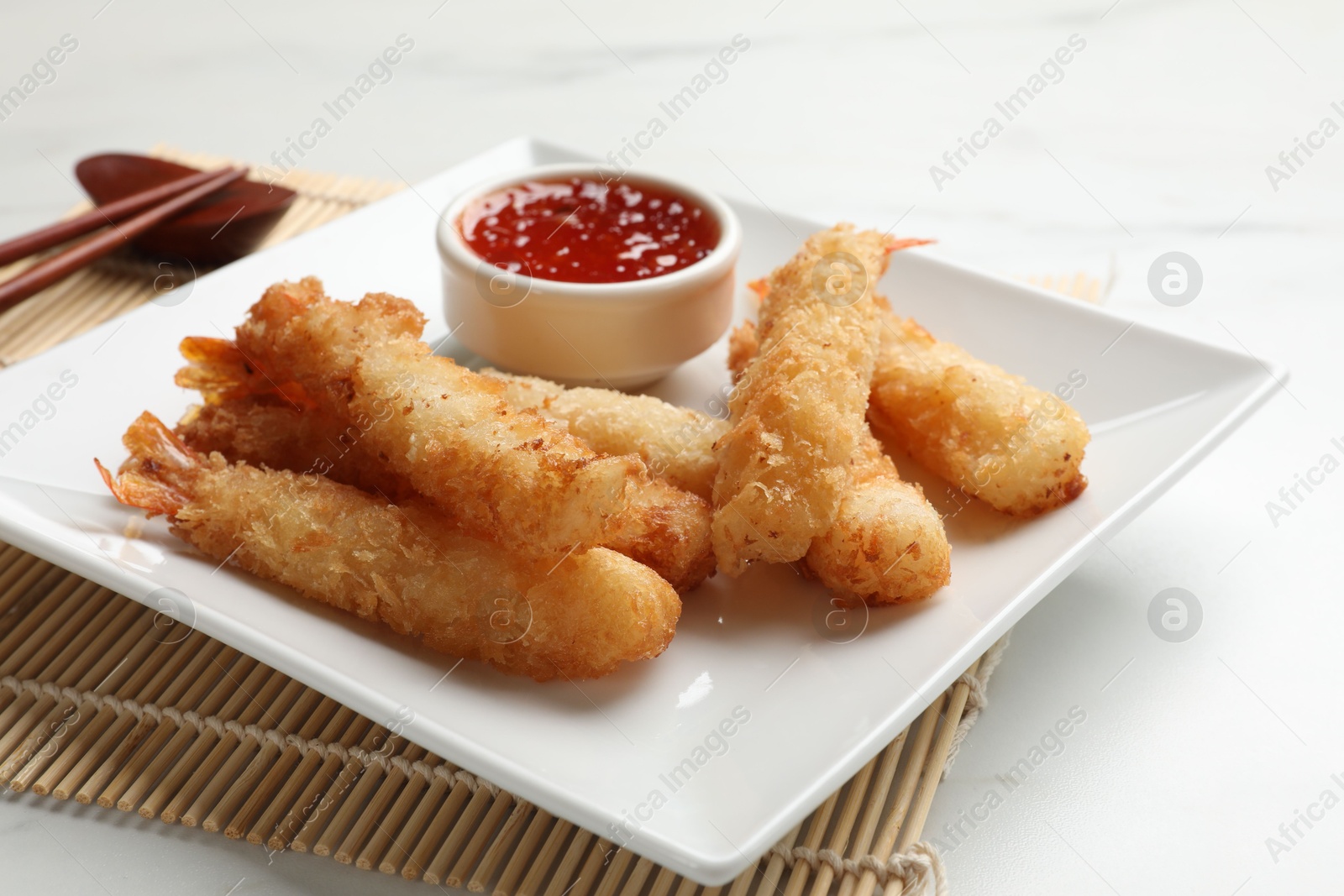 Photo of Tasty breaded fried shrimps served with sauce on white table, closeup