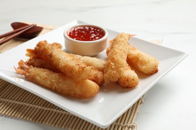 Photo of Tasty breaded fried shrimps served with sauce on white table, closeup