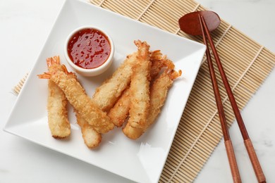 Tasty breaded fried shrimps served with sauce on white table, top view