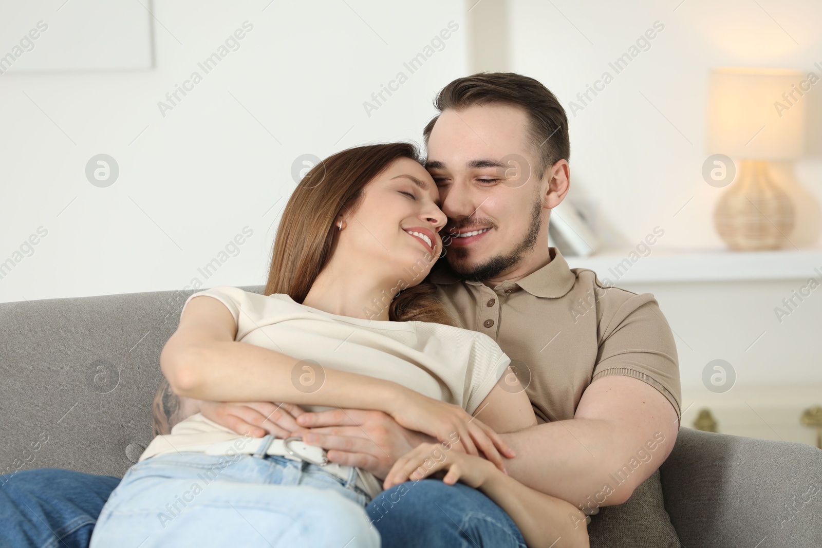 Photo of Happy couple hugging on sofa at home