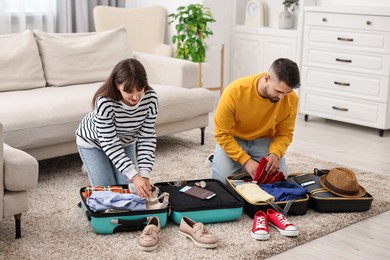 Couple packing suitcases for trip on floor at home