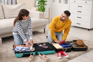 Couple packing suitcases for trip on floor at home