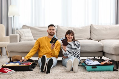 Photo of Couple with passports and tickets near suitcases on floor indoors