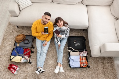 Photo of Couple with passports and tickets near suitcases on floor indoors, top view