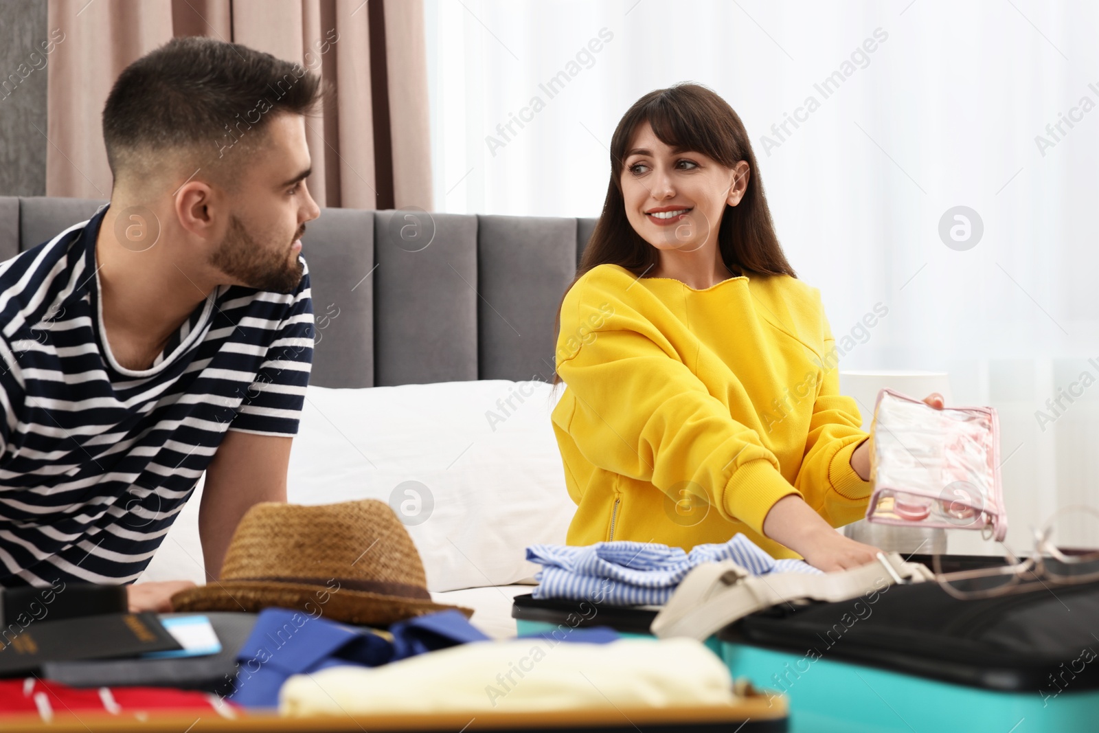 Photo of Couple packing suitcases for trip in bedroom