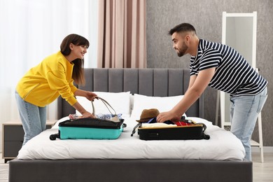 Photo of Couple packing suitcases for trip in bedroom