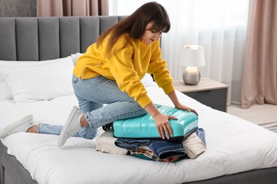 Woman packing suitcase for trip on bed indoors