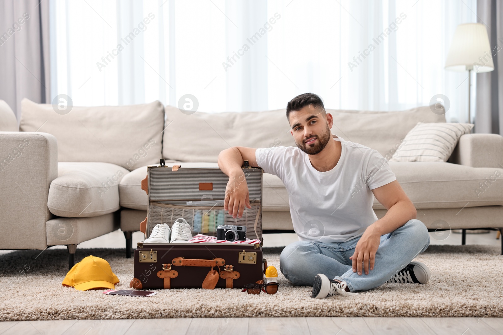 Photo of Man packing suitcase on floor at home