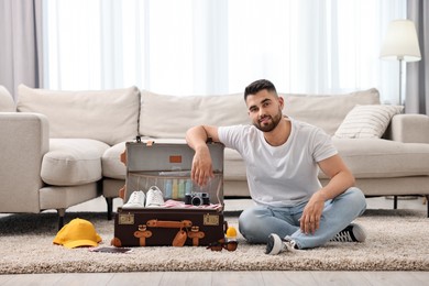 Man packing suitcase on floor at home
