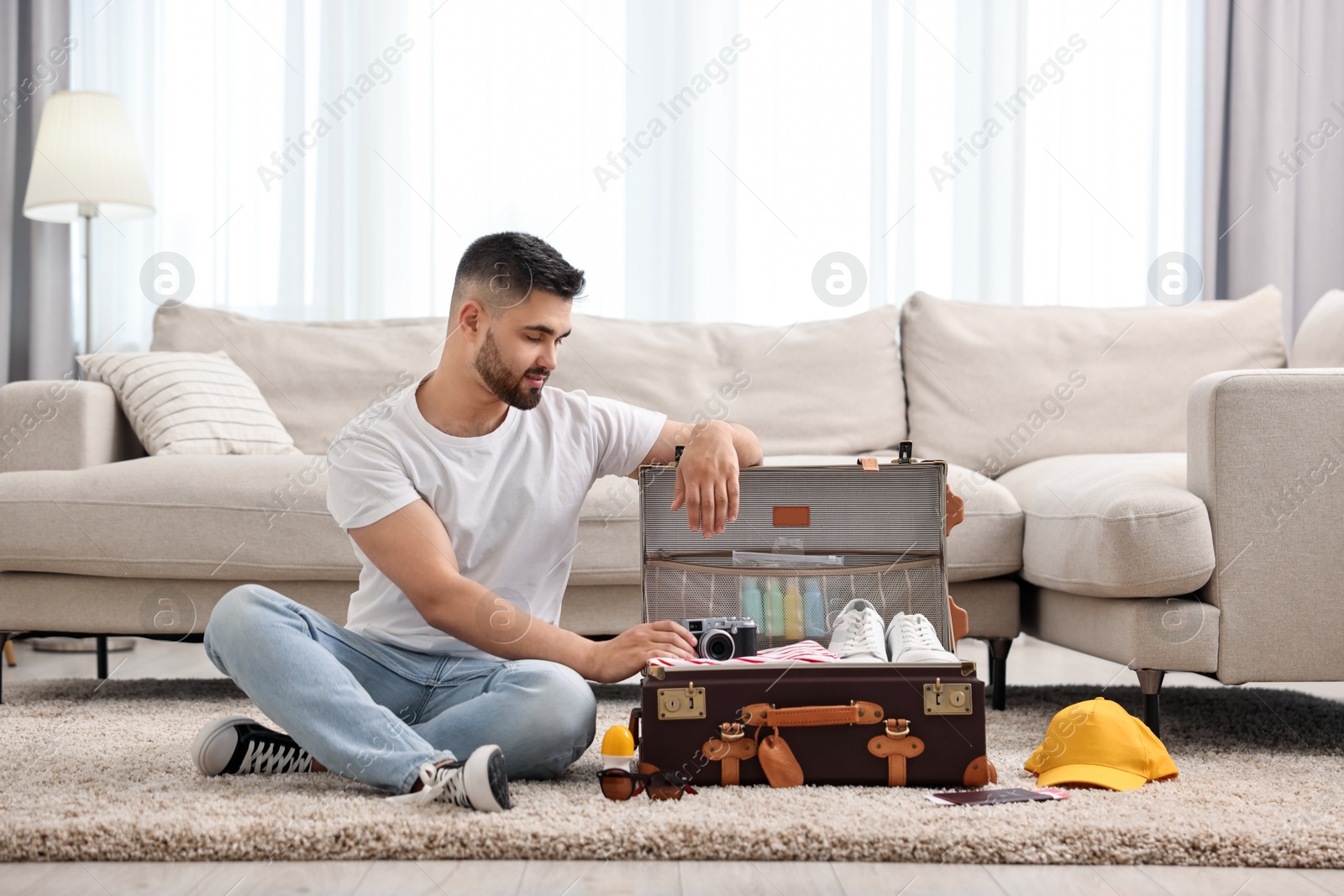 Photo of Man packing suitcase on floor at home