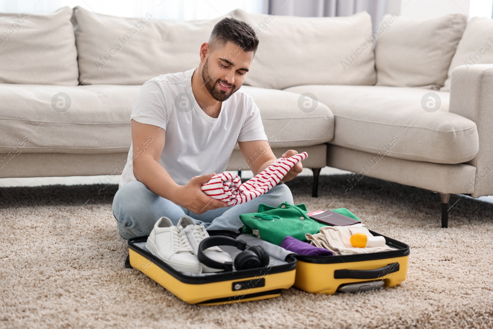 Photo of Man packing suitcase on floor at home