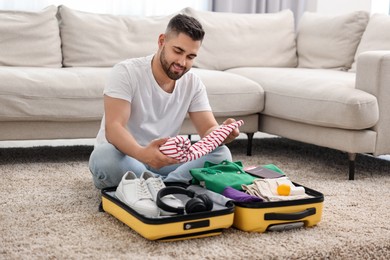 Man packing suitcase on floor at home