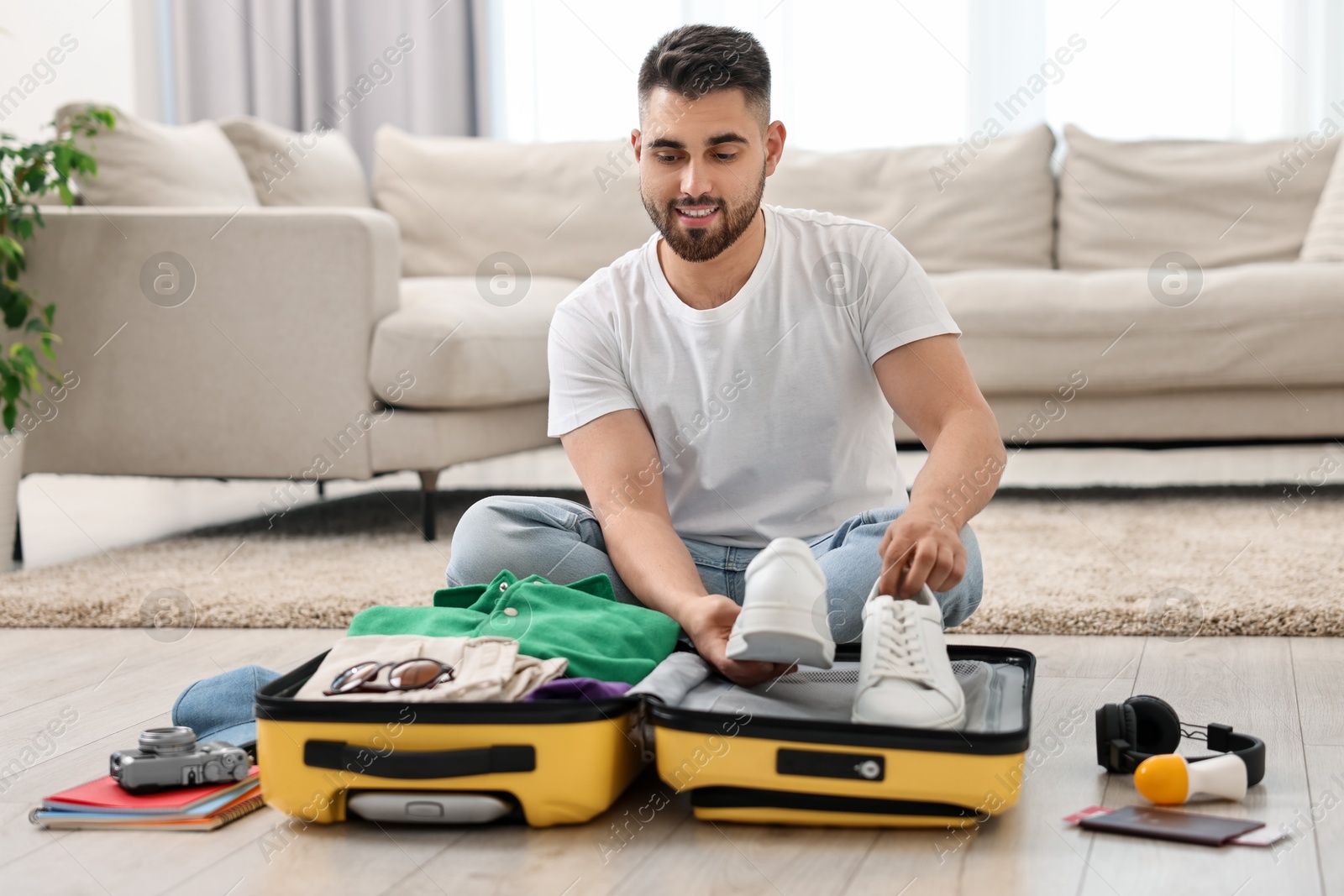 Photo of Man packing suitcase on floor at home