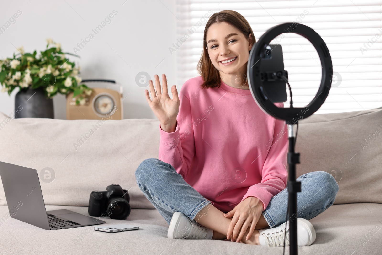 Photo of Technology blogger recording video with smartphone and ring lamp at home