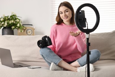 Technology blogger reviewing camera and recording video with smartphone and ring lamp at home