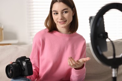 Photo of Technology blogger reviewing camera and recording video with smartphone and ring lamp at home