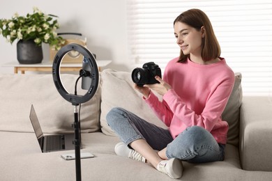 Technology blogger reviewing camera and recording video with smartphone and ring lamp at home