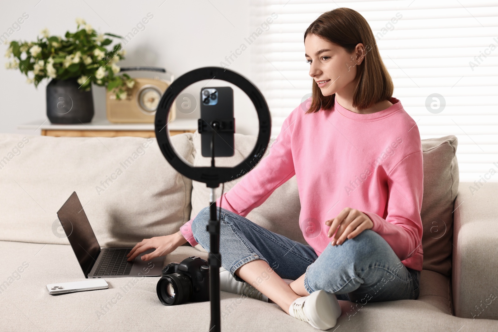 Photo of Technology blogger recording video with smartphone and ring lamp at home