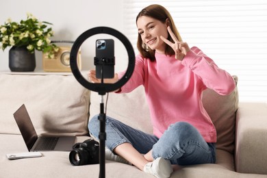 Photo of Technology blogger recording video with smartphone and ring lamp at home