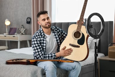 Photo of Music blogger recording guitar lesson with smartphone and ring lamp at home