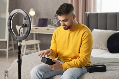 Photo of Technology blogger reviewing phone and recording video with smartphone and ring lamp at home