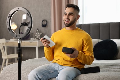 Photo of Technology blogger reviewing phone and recording video with smartphone and ring lamp at home