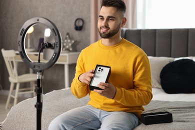 Photo of Technology blogger reviewing phone and recording video with smartphone and ring lamp at home