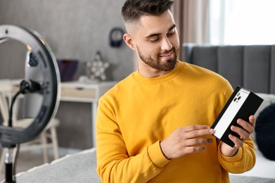 Photo of Technology blogger reviewing phone and recording video with smartphone and ring lamp at home