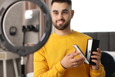 Technology blogger reviewing phone and recording video with smartphone and ring lamp at home