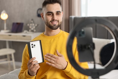 Photo of Technology blogger reviewing phone and recording video with smartphone and ring lamp at home