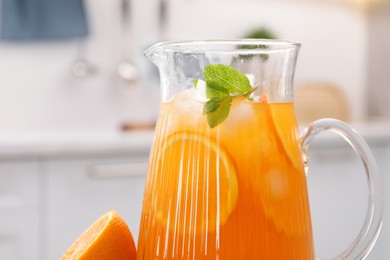 Photo of Freshly made lemonade in jug, mint and orange in kitchen