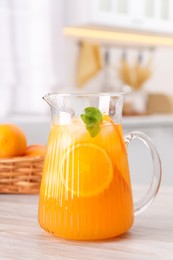 Photo of Freshly made lemonade in jug on wooden table in kitchen