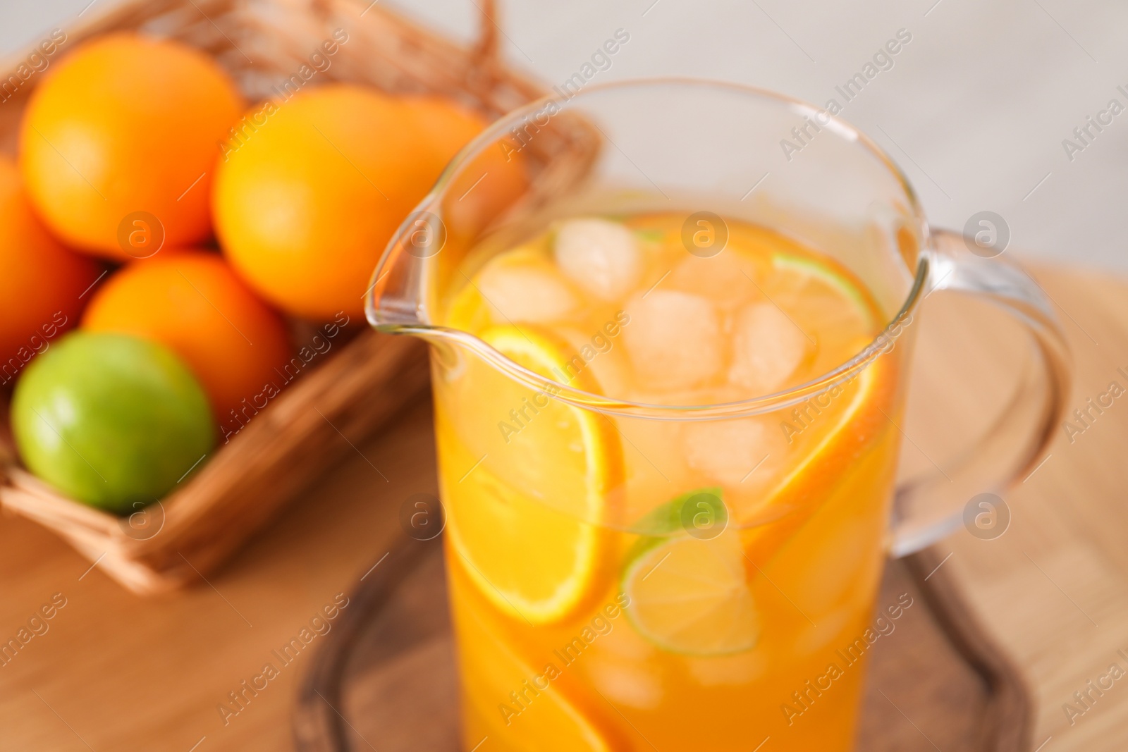 Photo of Freshly made lemonade in jug and citrus fruits on table, closeup