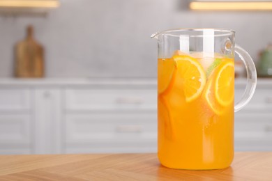 Freshly made lemonade in jug on wooden table in kitchen, space for text