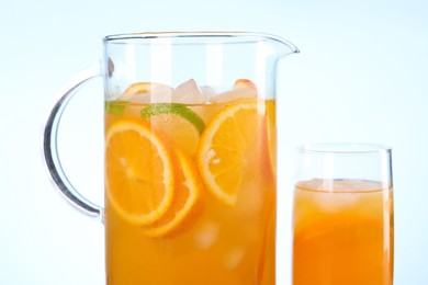 Freshly made lemonade in jug and glass against light blue background