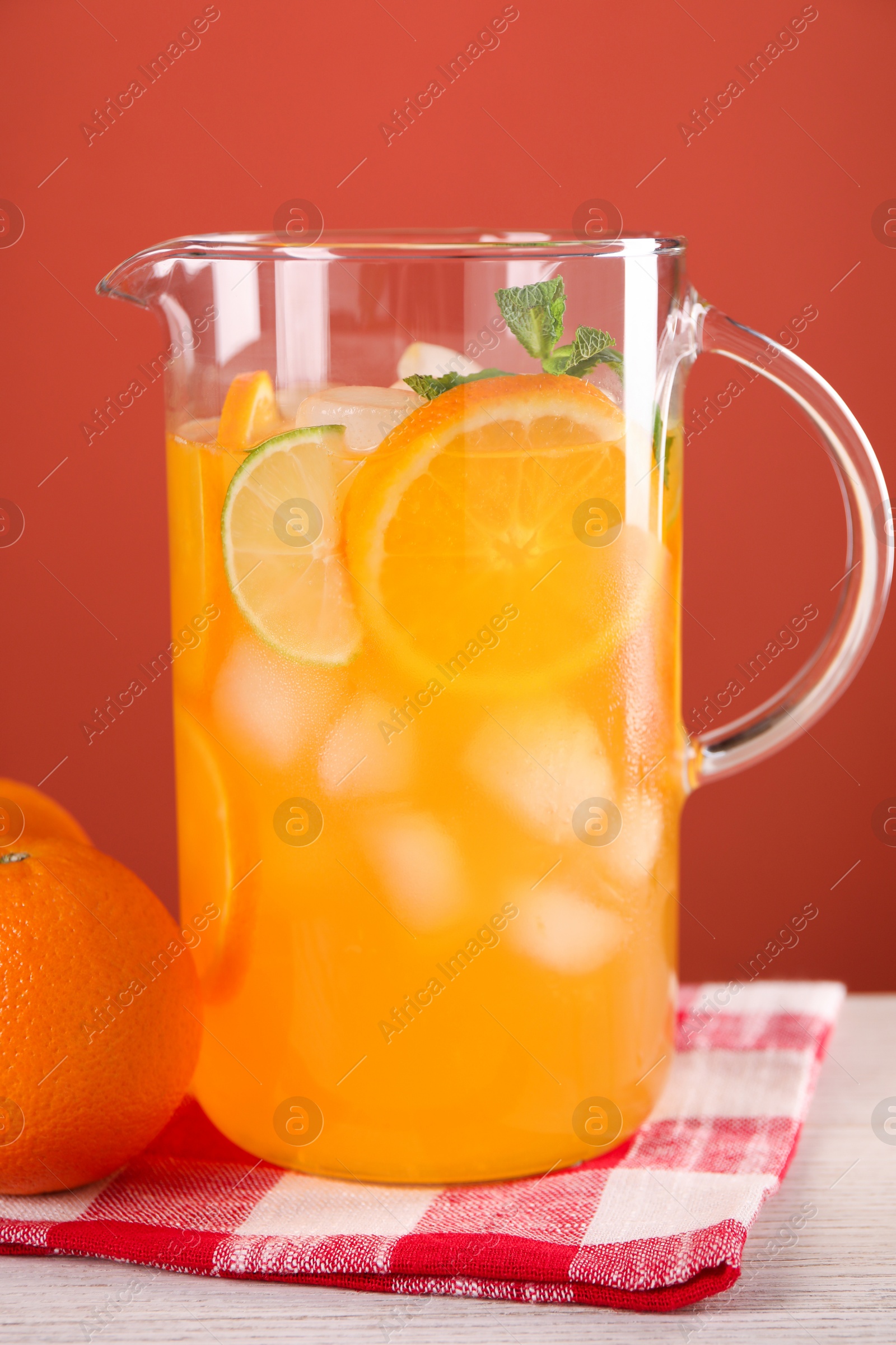 Photo of Freshly made lemonade in jug and orange on light wooden table