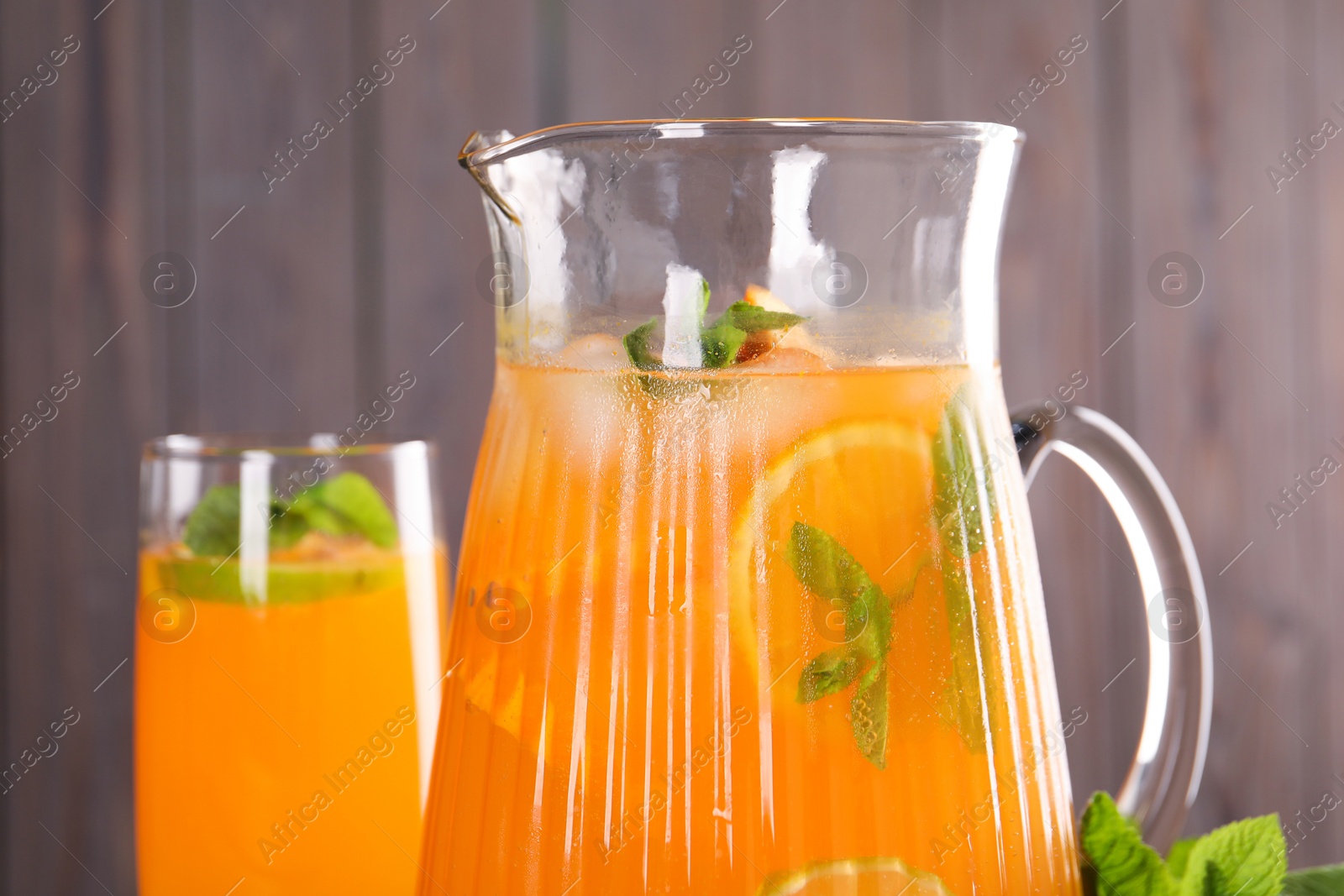 Photo of Freshly made lemonade in jug, glass and mint against blurred background